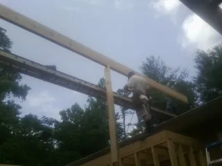 Carpenter setting a ridge beam over a new addition frame — Ice Dam Removal by Roofing Brothers in Loveville