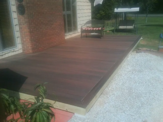 Freshly stained wood deck built against a brick home in Loveville