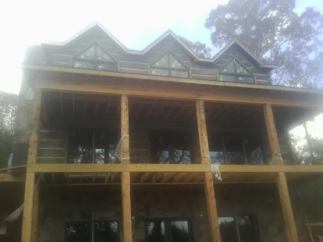 Dormers and porch framing on a large log home under construction — Roof Coating work by our crew in Loveville