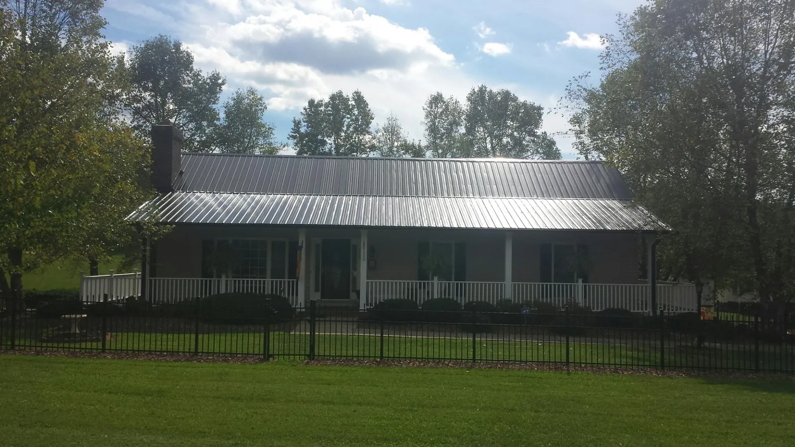 Gray metal roof on a brick ranch with a full width front porch — Gutter Guard Installation work by our crew in Loveville