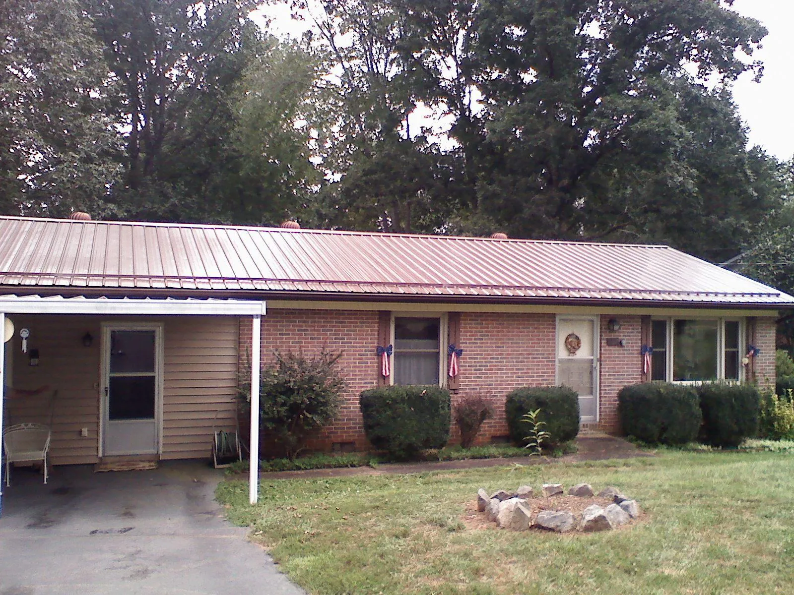 Bronze metal roof and carport on a brick ranch home — Roof Repair work by our crew in Loveville