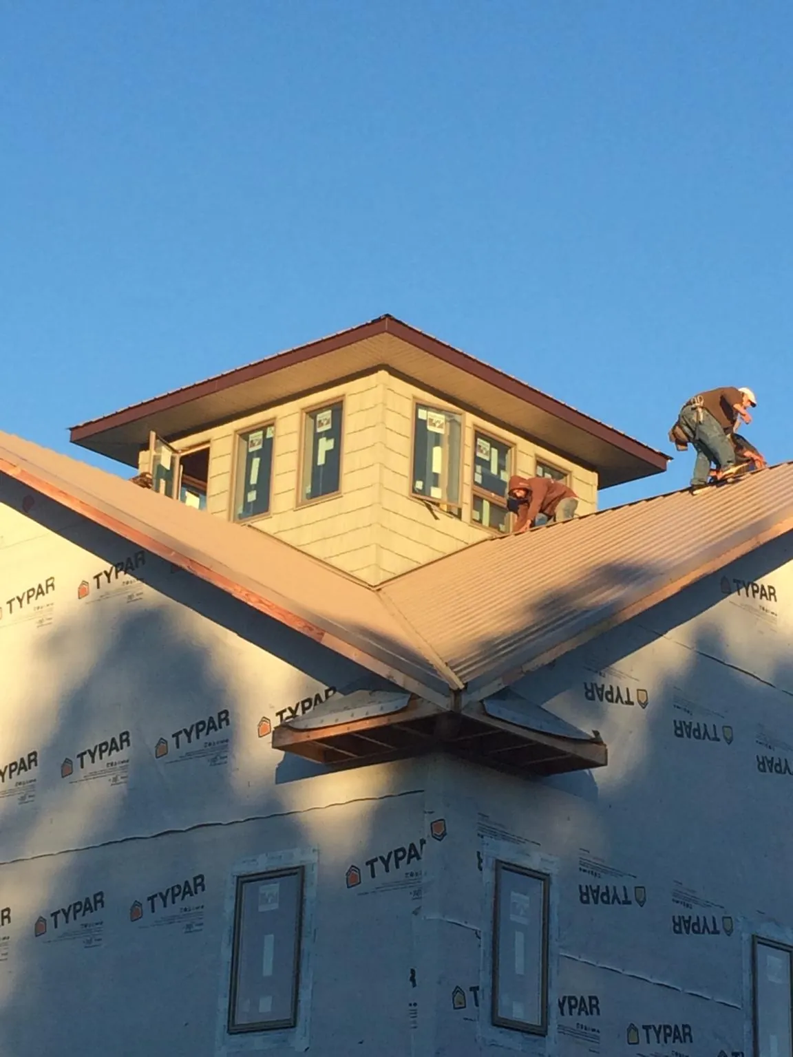 Roofers working around a rooftop cupola on a new metal roof at sunset — Roof Waterproofing in Loveville by Roofing Brothers